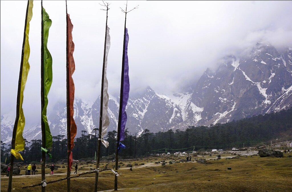 Multicolored flags & snow clad mountains at Yumthang valley in Lachung